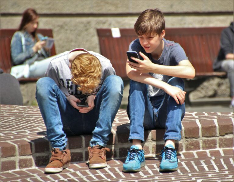 2 Adolescentes Sentados En El Piso Mientras Usa Su Teléfono Inteligente