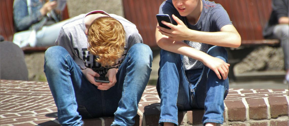 2 Adolescentes Sentados En El Piso Mientras Usa Su Teléfono Inteligente